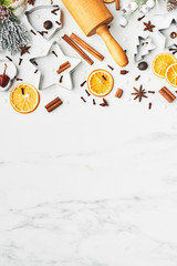 Holiday baking background for baking Christmas cookies with cutters, rolling pin and spices on white marble table with copy space for text. Top view.