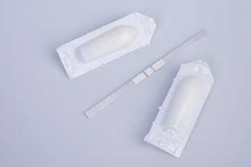 Suppositories and pregnancy test on the white background. ABORTION CONCEPT.