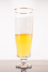 Glass of fresh beer with cap of foam isolated on a white background. Half empty pint of  light beer on white background.