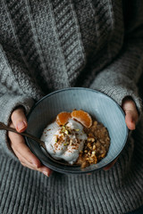 wiman has breakfast gluten-free porridge with berries, nuts and delicious lactose-free vegetarian yogurt. Healthy morning concept, cold winter morning.