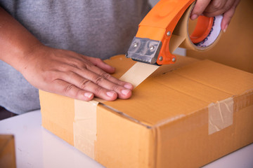 The staff is using the tape to pack the package goods to the customer.