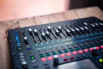 The DJ is adjusting the volume of the sound. Professional audio mixing console