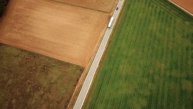 Aerial shot of country road with traveling vehicles