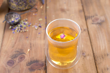 Tea in a glass with lavender on a wooden background. Hot drinks for health.