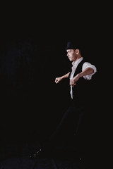 male dancer in hat on black background in motion