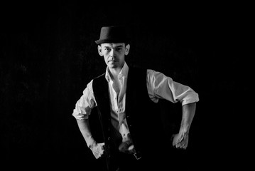 A serious old-fashioned man in a hat posing on a dark background. brutal man