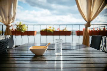 an empty plate and an empty glass on a wooden table in a summer cafe.