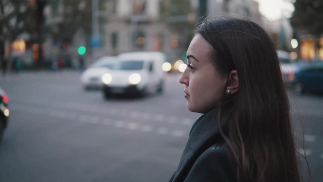 4k shot of a tired sad girl waiting to cross the street. City traffic on background.