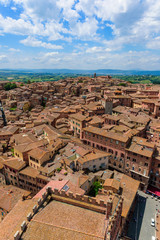 Fototapeta premium Historic town Siena, Tuscany - Aerial view with beautiful landscape scenery on a sunny summer day, walled medieval hill town with towers in the province of Siena, Italy- Europe