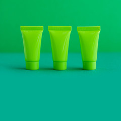 3 three blank green cosmetic tubes on green background. Simple plastic containers, mock up packaging design. shallow depth of field, copy space photography