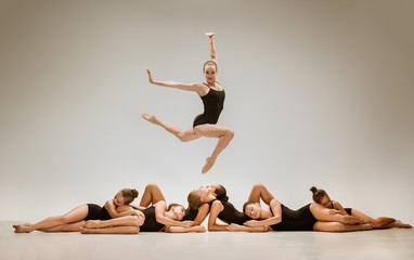 Obraz premium The group of modern ballet dancers dancing on gray studio background