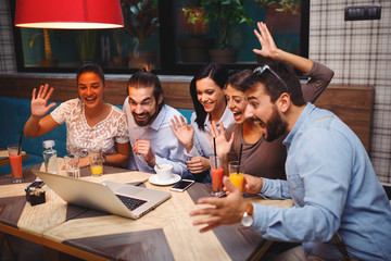 Group of friends making video call through the laptop in the cafe