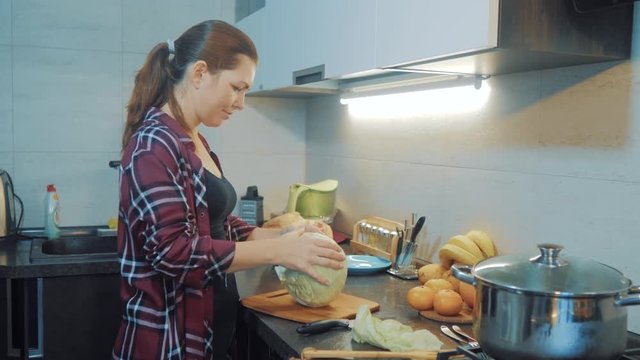 woman in the kitchen preparing a meal concept. girl in the kitchen cuts cabbage with a knife. cook vegetarian food healthy food. girl at home in the kitchen slow motion video lifestyle