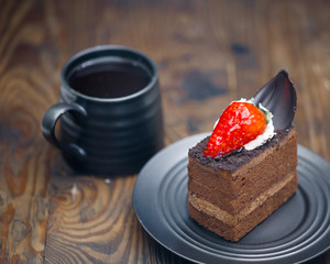 Chocolate cake in saucer next to mug of coffee on distressed wood