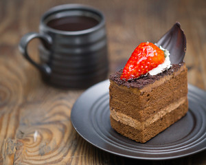 Chocolate cake in saucer next to mug of coffee on distressed wood