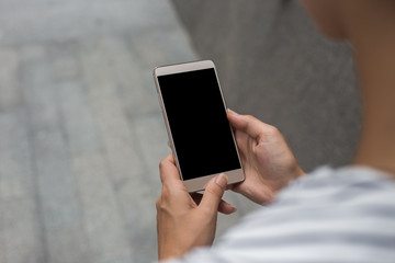 Cropped shot view of womans hands holding smart phone with blank copy space screen for your information content about app, logo or copy, reading text message on cell telephone during in urban setting