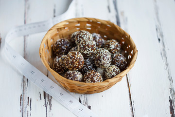 healthy energy organic bites with nuts, dates, honey and sesame in a plate and centimeter on a light wooden background.