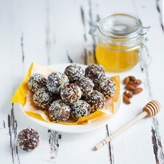 healthy energy organic bites with nuts, dates, honey and sesame in a plate on a light wooden background.