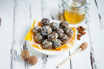 healthy energy organic bites with nuts, dates, honey and sesame in a plate on a light wooden background.