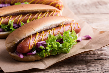 Hot dog with yellow mustard, lettuce and onions