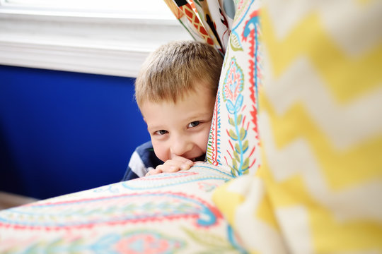 Lovely Little Boy In Striped Jumper Playing Hide And Seek At Home