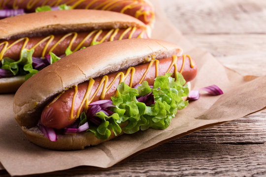 Hot dog with yellow mustard, lettuce and onions