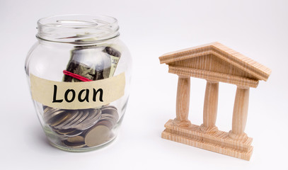 Glass jar with coins and the word Loan and a state building. Borrow money, Take a loan or a credit from a bank. Deposit concept. Financial management and successful credit.