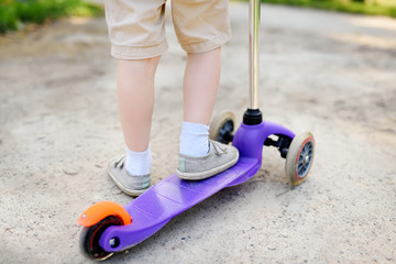 Toddler boy learning to ride scooter. Feet close up.