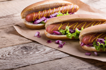 Hot dog with yellow mustard, lettuce and onions