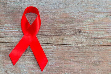 Red Ribbon - AIDS awareness symbol on the wooden background with copy space