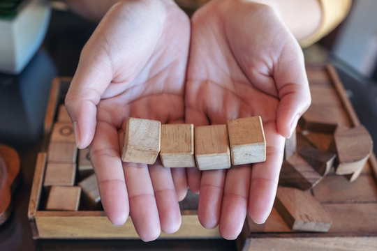 Top view image of woman's hands holding and showing four square wooden blocks