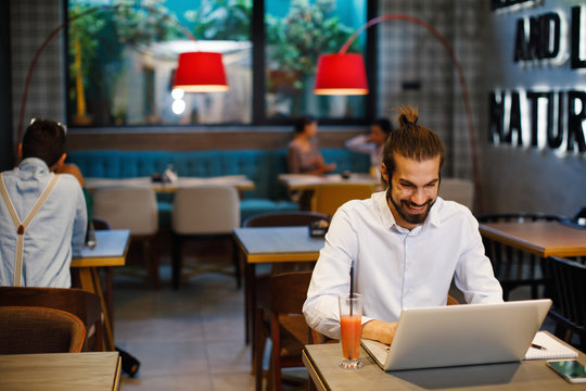 Young happy businessman using a laptop in a coffee shop