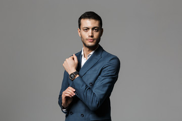 Image of brunette arabic businessman 30s in formal suit looking at camera and demonstrating...