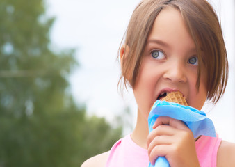 Pretty little girl eating licking big ice cream in waffles cone happy laughing on nature background