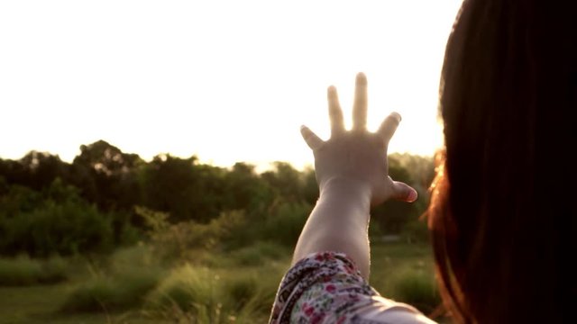 Sunlight through female hands while her looking at sun and hands raised, inspiration. Slow motion shot in 50 fps