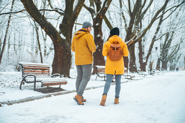 couple walking by snowed city park talking socializing. romantic date in winter time