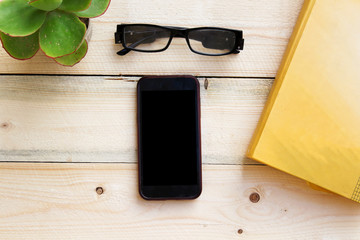 top view image of smart phone and notebook on wooden background