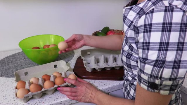 Woman puts fresh, brown chicken eggs in a bowl