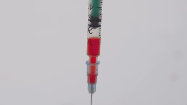 syringe slowly drawing blood on a white background