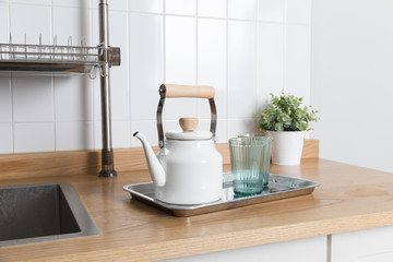 Clean dishes drying on metal dish rack on light background. Kitchen utensils and dishware on wooden shelf. Kitchen interior background.Text space.
