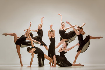 Fototapeta premium The group of modern ballet dancers dancing on gray studio background