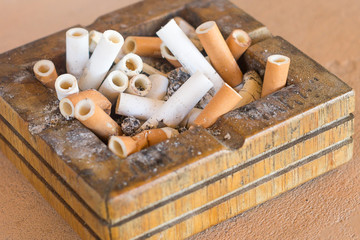 wooden ashtray filled with cigarette butts