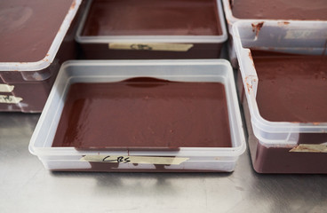 Melted chocolate in trays on a confectionary making factory table