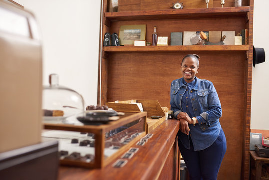 Smiling entrepreneur standing by a counter in her chocolate shop