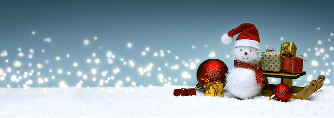 Christmas snowman with gifts on the sledge and snowfall.