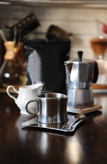 Coffee in moka pot. Stainless steel cup. Devices for manual coffee brewing in the background