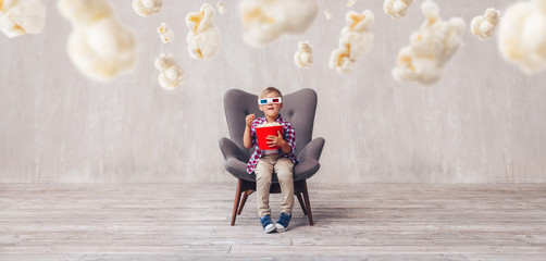 Happy boy in 3d glasses with popcorn indoors