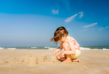belle jeune fille faisant des pâtés de sable