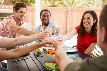 Adult friends sitting at a table outdoors making a toast