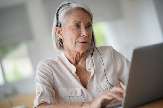   Senior Woman Working On Computer With Headset